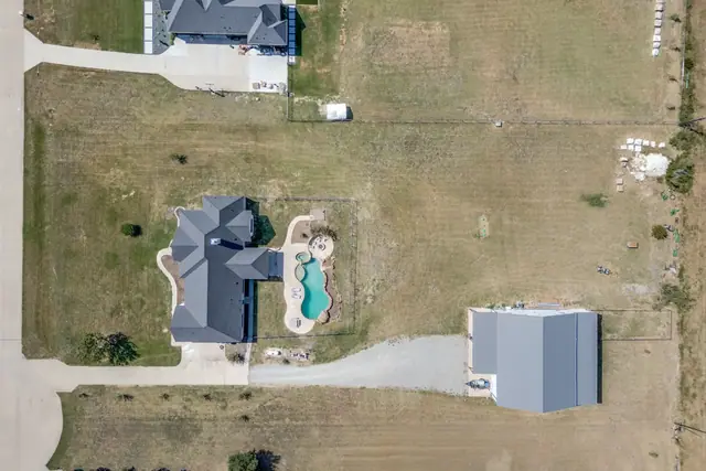 Aerial view of the lot showing the home, pool, and workshop/barn