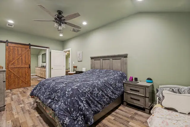 Bedroom with a bed, nightstand, and a wood sliding barn door opening to a bathroom