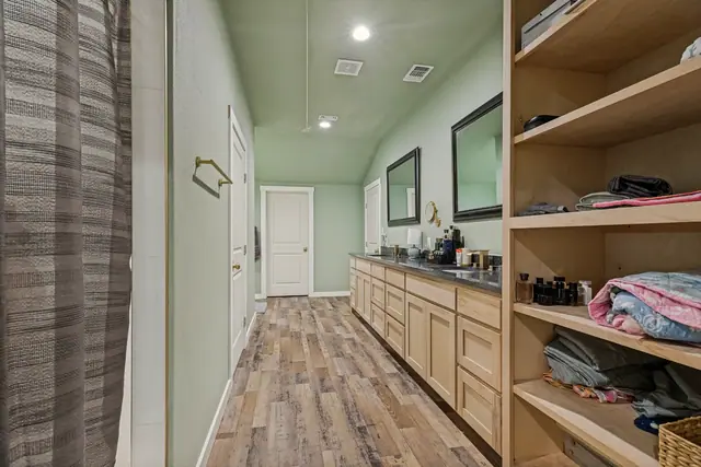 Bathroom with a long double vanity, mirrors, and open shelving with linens