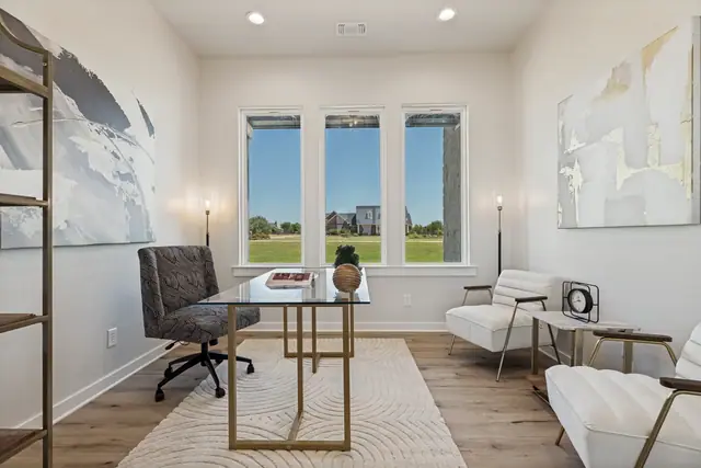 Study with a desk, shelving, and windows looking over the lawn