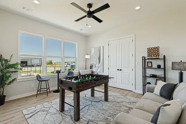 Flexible living room with a game table, seating, and windows along one wall