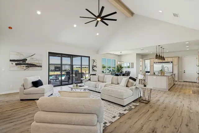Open living area with a vaulted ceiling, ceiling fan, and seating that opens to the kitchen