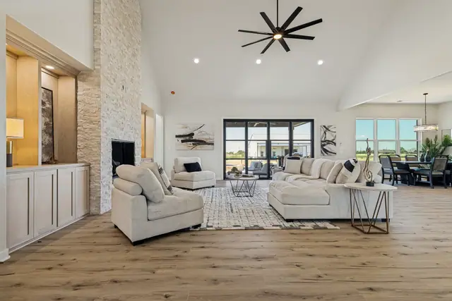 Living room with a stone fireplace, built-in cabinetry, and tall windows