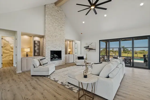 Living area with a stone fireplace and sliding glass doors leading to the covered patio