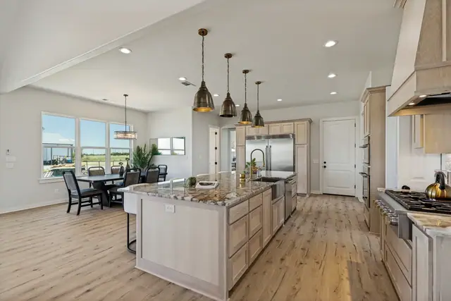 Kitchen with an oversized island, pendant lights, and the dining room beyond