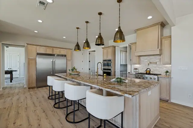Kitchen island with bar stools, sink, and stainless appliances