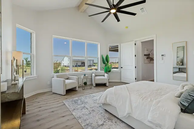 Bedroom with a bed, seating area, and windows facing the lawn