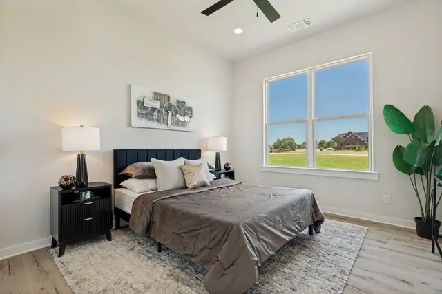 Bedroom with a bed, nightstand, and a window looking out over the property