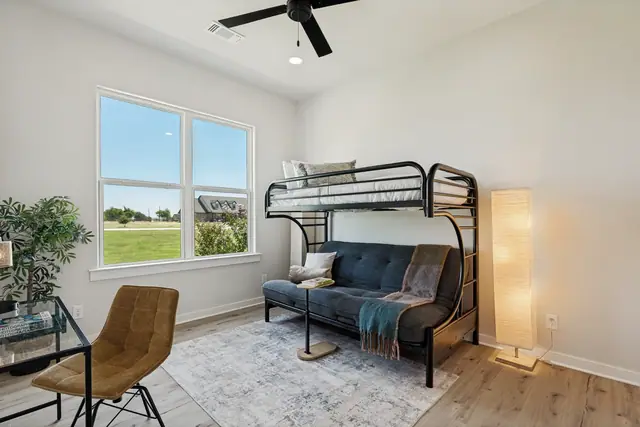 Bedroom with a metal bunk bed over a sofa, a desk, and windows