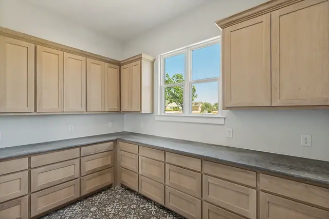 Wall of light wood cabinets with counter space and a window