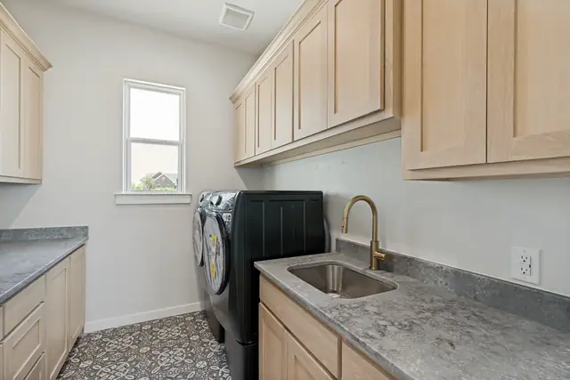 Laundry room with a washer and dryer, sink, counter, and upper cabinets