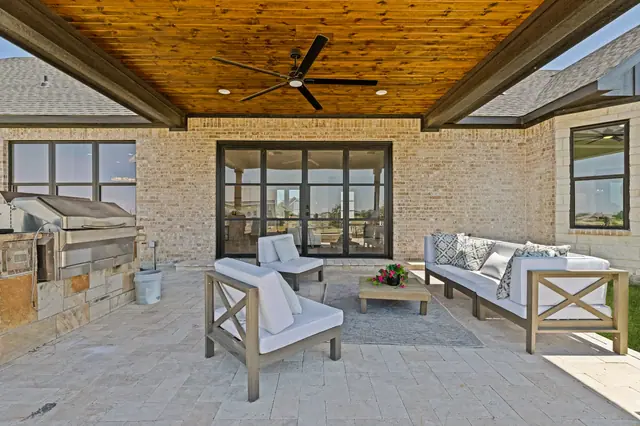 Covered patio with a wood ceiling, ceiling fan, seating, and a built-in grill