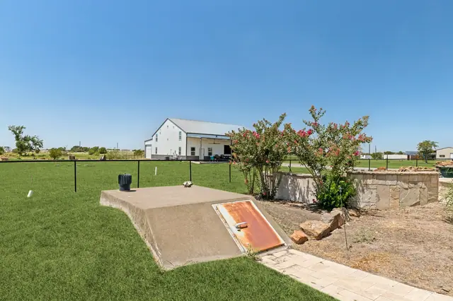 Back lawn with planting beds and the workshop/barn in the distance